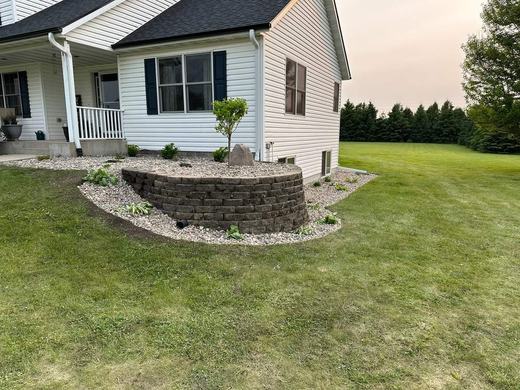 Finished stacked stone planter bed with river rock after service